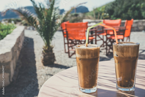 Coffee frappe, greek cuisine on the table at the beach, vintage look photo