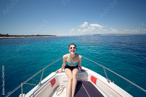 Beautiful woman standing on shipboard and getting ready to sail away to an open sea. Woman on her private boat on a sunny summer day. Luxury vacation at sea. Getting fascinated by sea life.Honeymoon