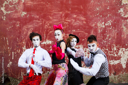 Four mimes standing in a fighting pose on a background of a red