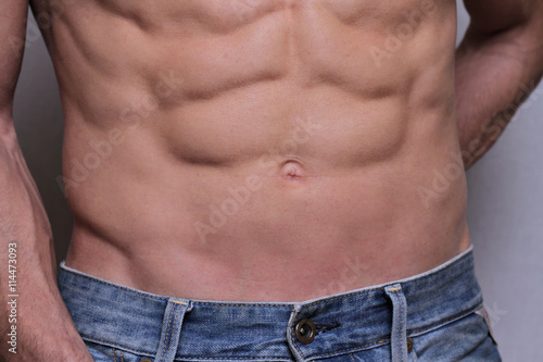 Strong Athletic Man showing muscular body and sixpack abs over white background close up