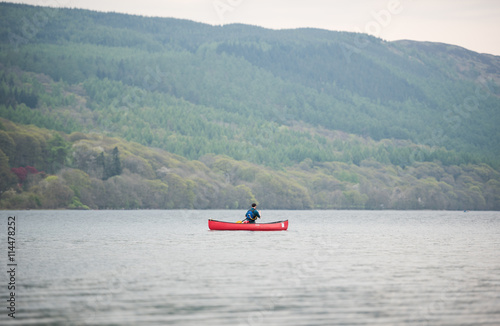 Lake Coniston, England, 06/06/2016, A lonely canoeist  on lake coniston, The Lake District, with a foggy green forest backdrop.
