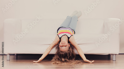 Obraz na plátne Little girl kid with long hair upside down on sofa