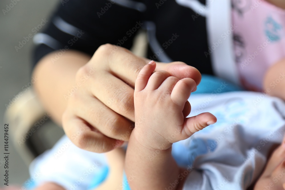 Photo of newborn baby feet and hand in soft focus