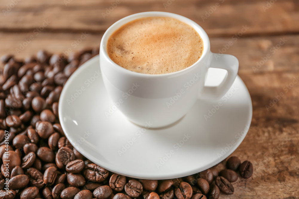 Cup of coffee with beans on wooden table Cup of coffee with beans on wooden table