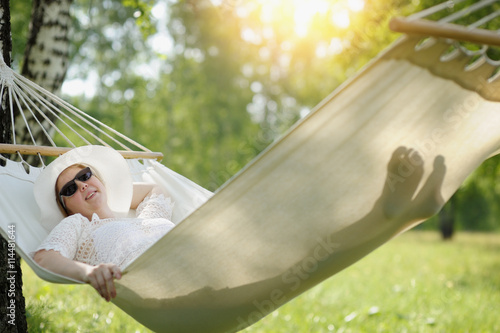 Woman in glasses relaxing in the hammock outdoors.