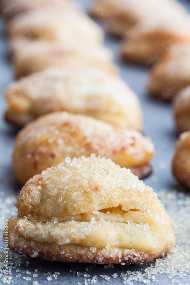 Vertical row of cottage cheese cookies sprinkled with sugar. Shallow depth of field.