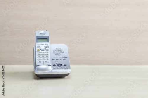 Closeup gray phone , office phone on blurred wooden desk and wall textured background in the meeting room under window light