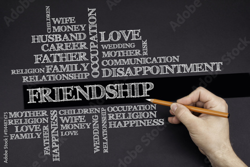 Hand with a white pencil writing: Friendship word cloud