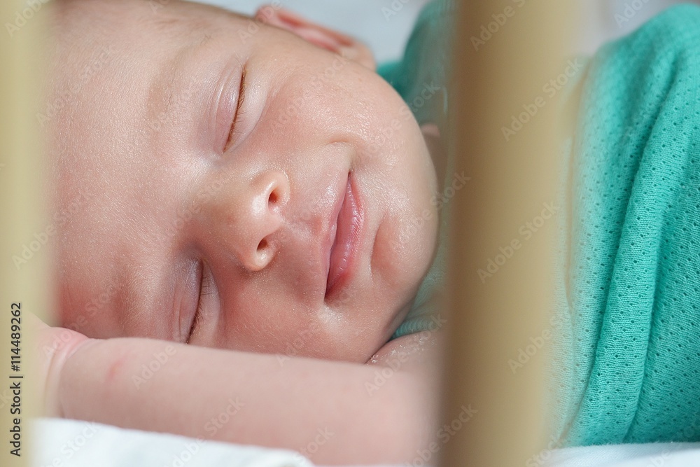 Smiling newborn baby sleeping in a cot Smiling newborn baby sleeping in a cot
