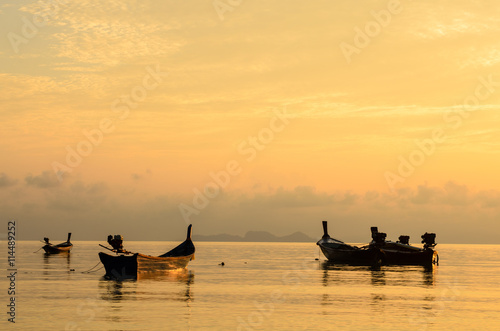 Fishing boats floating on the sea with golden sunset sky background, summer time.