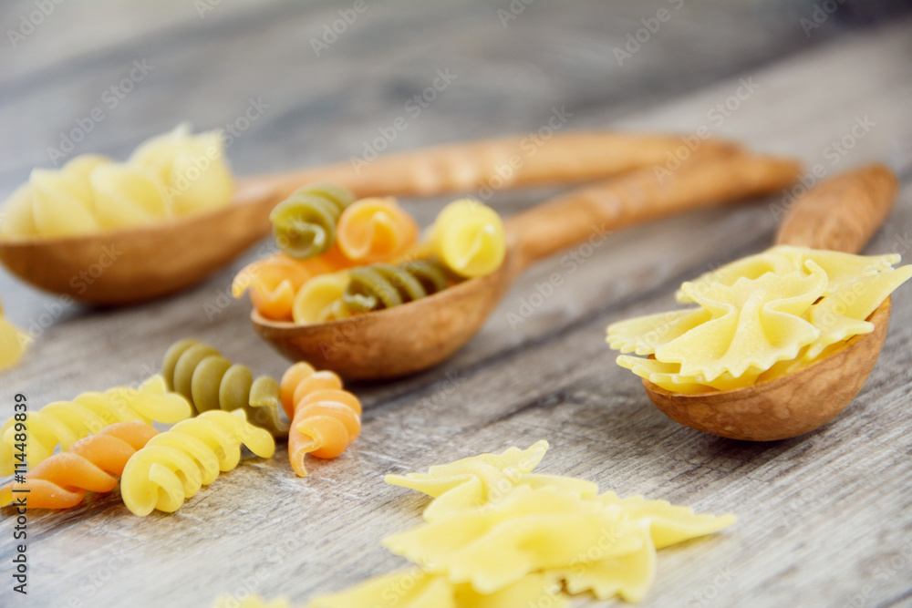Three kinds of raw pasta in wooden spoons Three kinds of raw pasta in wooden spoons