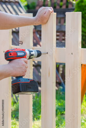 building a wooden fence with a drill and screw. Close up of his