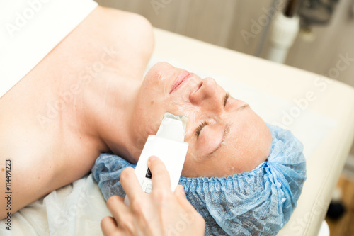 Young woman lying down in a spa salon and having a Ultrasonic face cleaning. The cosmetic procedures for the face. Beauty treatments in the spa salon. Facial Skin Care
