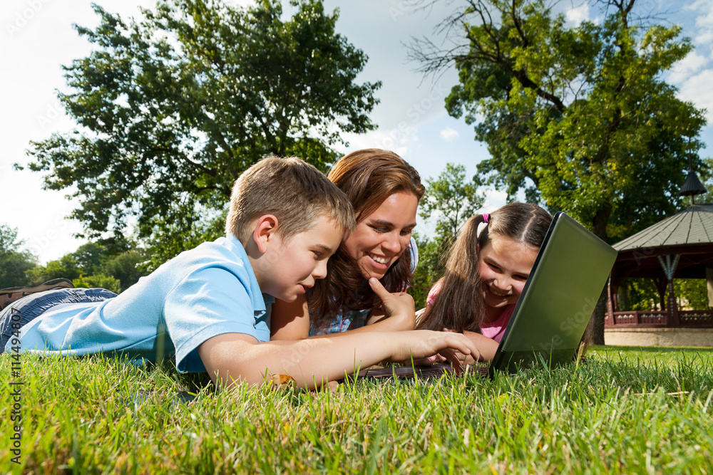 Happy Family using laptop lying on grass Happy Family using laptop lying on grass
