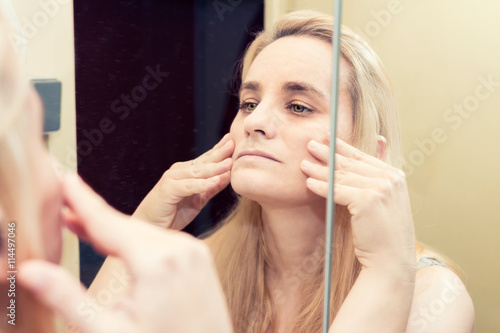 Blonde woman looking at her reflection in the mirror