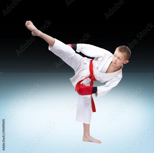 An athlete dressed in white doing a high kick