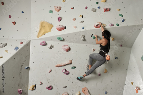 Girl climbing indoors, view from the back