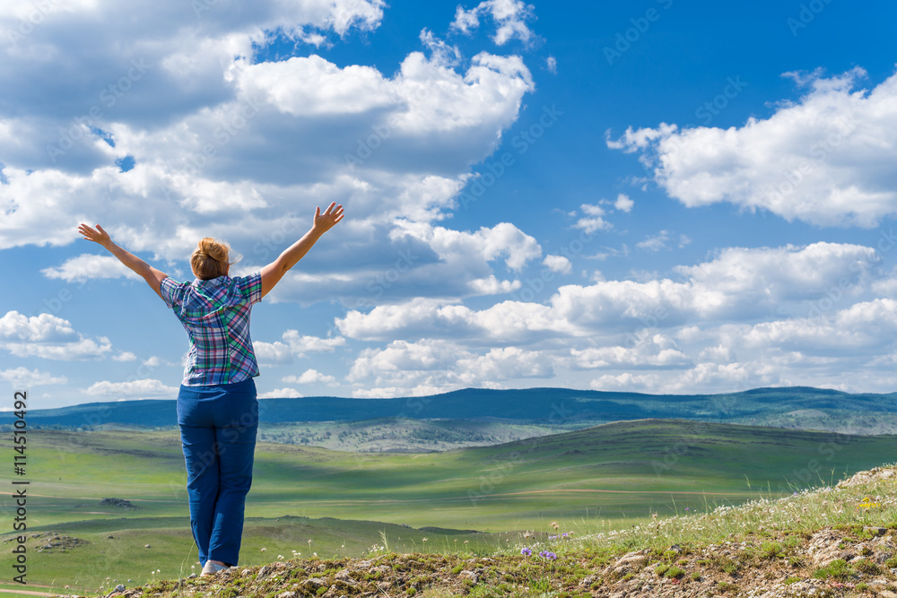 Woman enjoying the view of the steppe, hills and blue sky Woman enjoying the view of the steppe, hills and blue sky