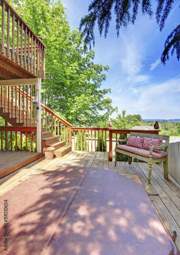 Two level backyard deck with bench and hot tub for enjoyment on the first level.