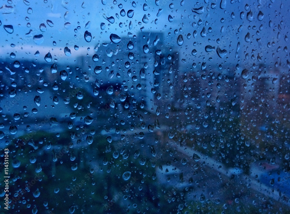 Urban view from office window with rain drops falls on a window during ...