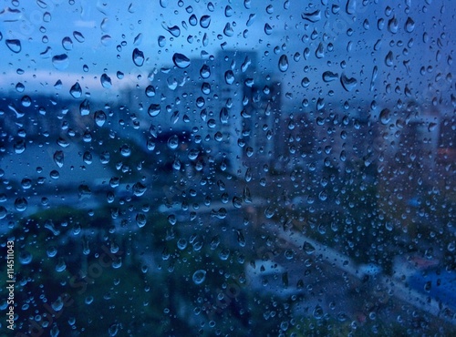 Urban view from office window with rain drops falls on a window during a stormy day