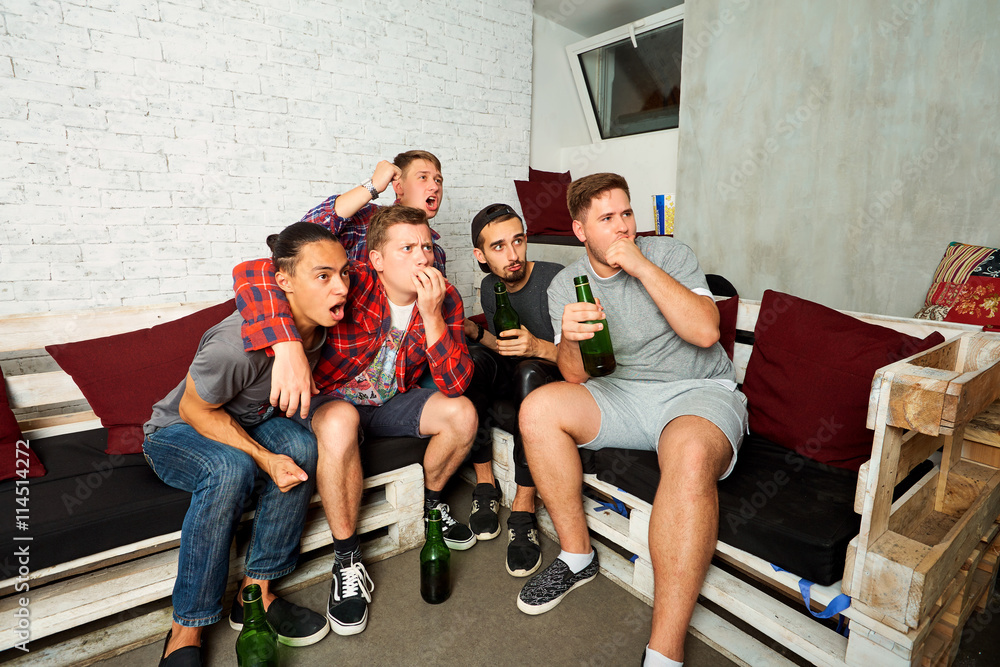 Friends emotionally watching football on TV. Fans drink beer and Friends emotionally watching football on TV. Fans drink beer and