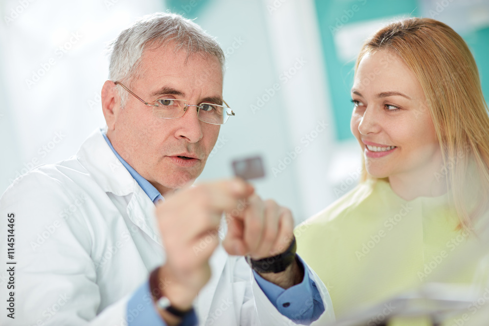 Obraz premium Dentist explains to female patient problem with tooth using dent