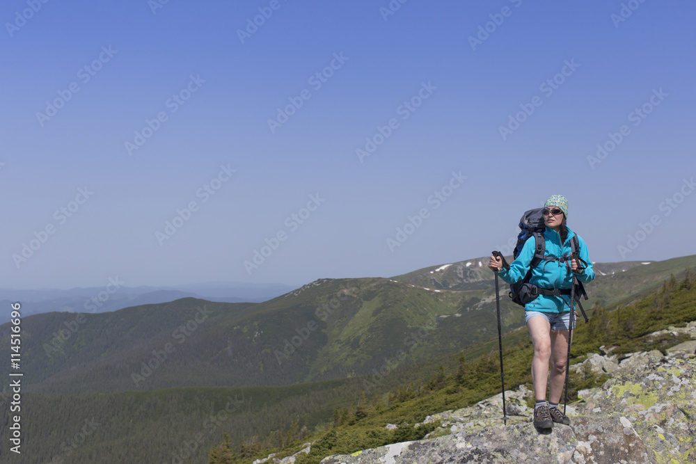 Girl with a backpack in a mountain hike in the summer.