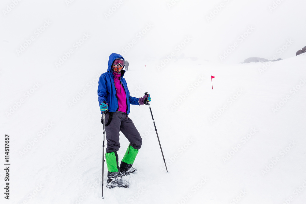 Mountain hiking group with trekking poles sticks having hard climbing trip in winter snow storm