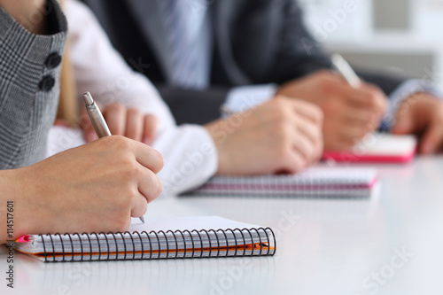 Close up view of students or businesspeople hands writing someth