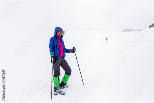 Mountain hiking group with trekking poles sticks having hard climbing trip in winter snow storm