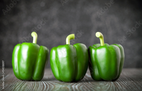 Fotografia Green bell pepper on wooden board dark background front view