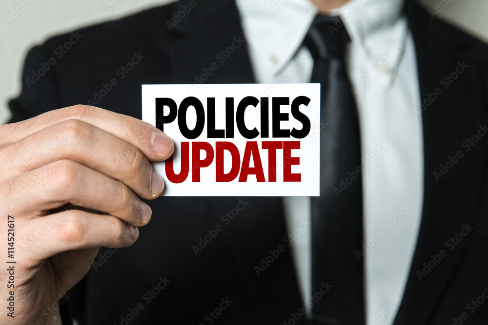 Business man holding a card with the text: Policies Update Business man holding a card with the text: Policies Update