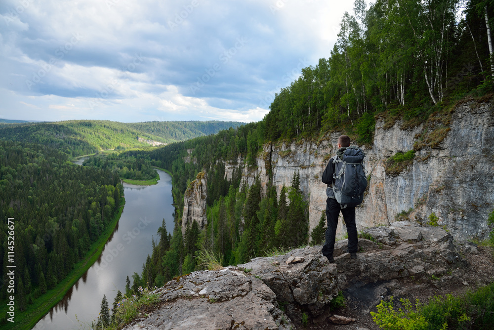 man with backpack stands on top of the mountain.