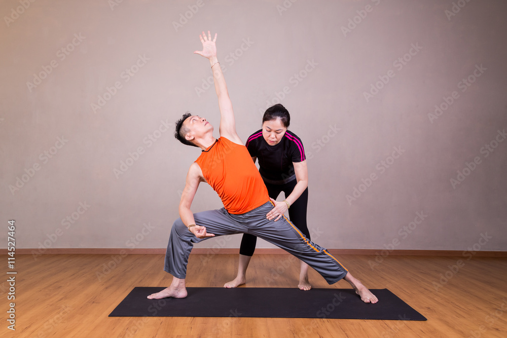 Fototapeta premium Yoga instructor guiding student perform extended side angle pose