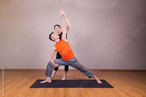 Yoga instructor guiding student perform extended side angle pose