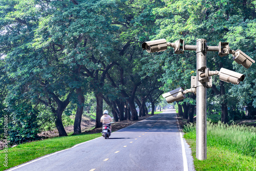 Security camera for monitring a road with shadow of tree tunnel. photo