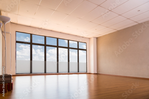Empty yoga and dance studio with wooden flooring, windows with blue sky