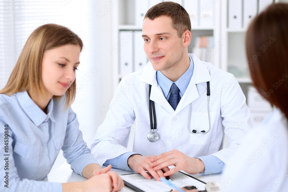 Doctor and patient sitting at the table in medical cabinet. High level and quality medical service concept. Doctor and patient sitting at the table in medical cabinet. High level and quality medical service concept.