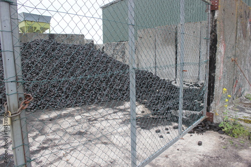 Heap of coal briquets behind a wire mesh gate