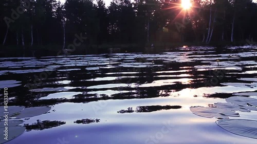 Video of lake at sunrise withforest in the background and in the reflection. photo