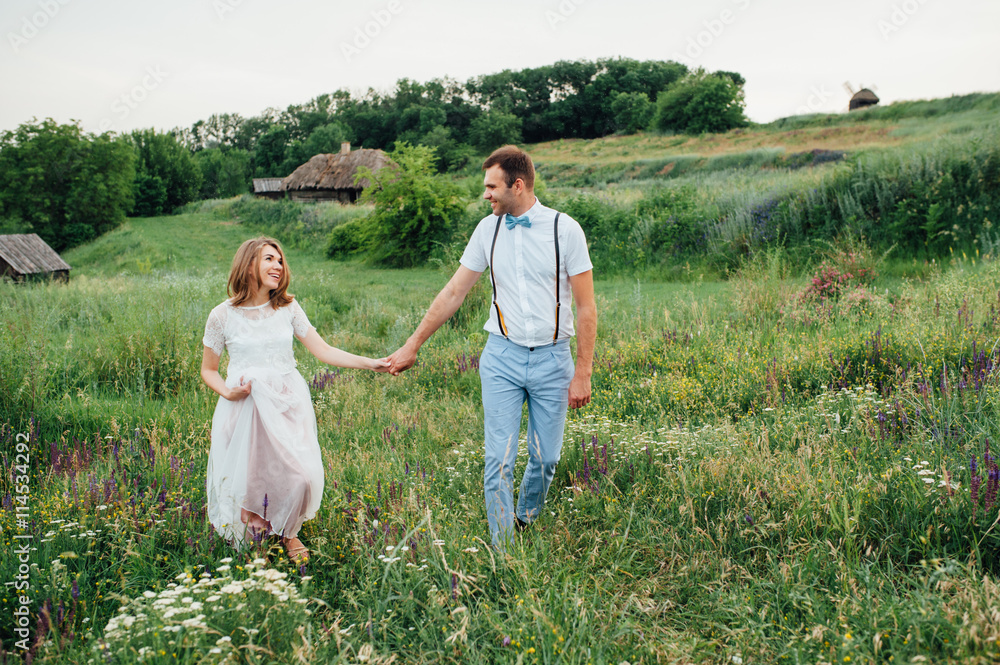 Fototapeta premium Happy Bride and groom walking on the green grass