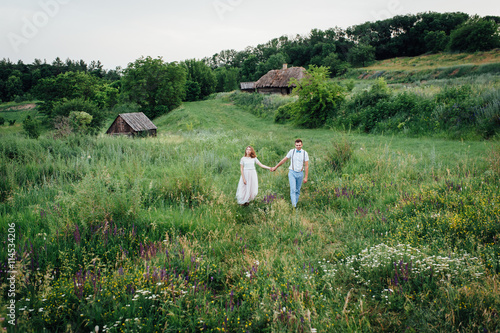 Happy Bride and groom walking on the green grass
