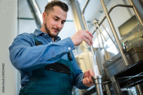 Tableau sur toile Brewer checking beer with hydrometer