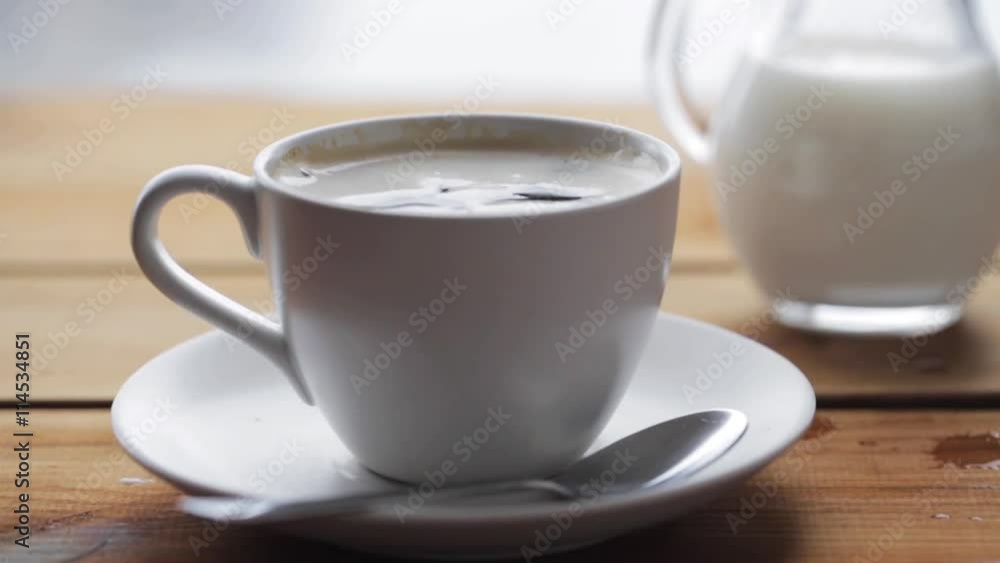 hand dropping sugar into coffee cup on table hand dropping sugar into coffee cup on table
