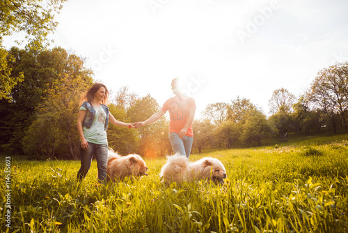 Wall Mural Young couple with the dogs in the park.