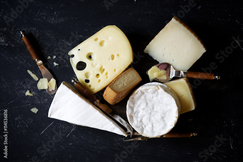 Different types of cheese with accessories for cheese on a dark background 
