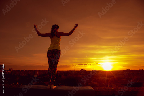 Fototapeta Naklejka Na Ścianę i Meble -  Young girl yoga on the roof. Silhouette