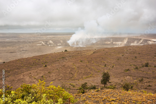 Smoking Halema uma u Crater in the Kilauea Caldera as seen from the Jaggar museum overlook. photo