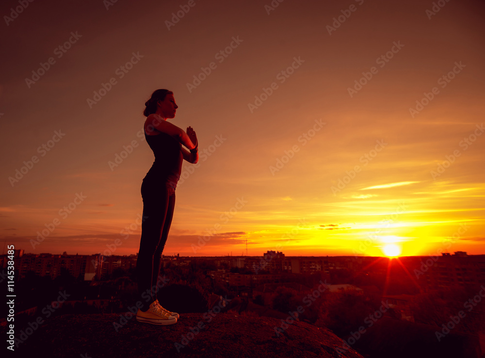 Young girl yoga on the roof. Silhouette
